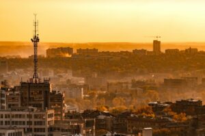 Telecommunication tower with cellular network antenna on city background